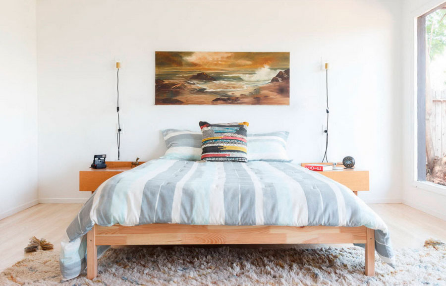 Деревянная кровать, текстиль с голубыми полосами, поглощающая внимание картина на стене, ковёр с высоким ворсом для комфорта и уюта