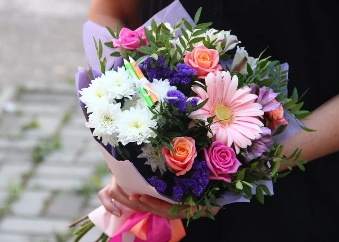 Жінка тримає букет квітів з троянди, хризантеми і Гербера, різнокольорове квіткове оформлення, подарунок на вулиці, свіжі квіти.