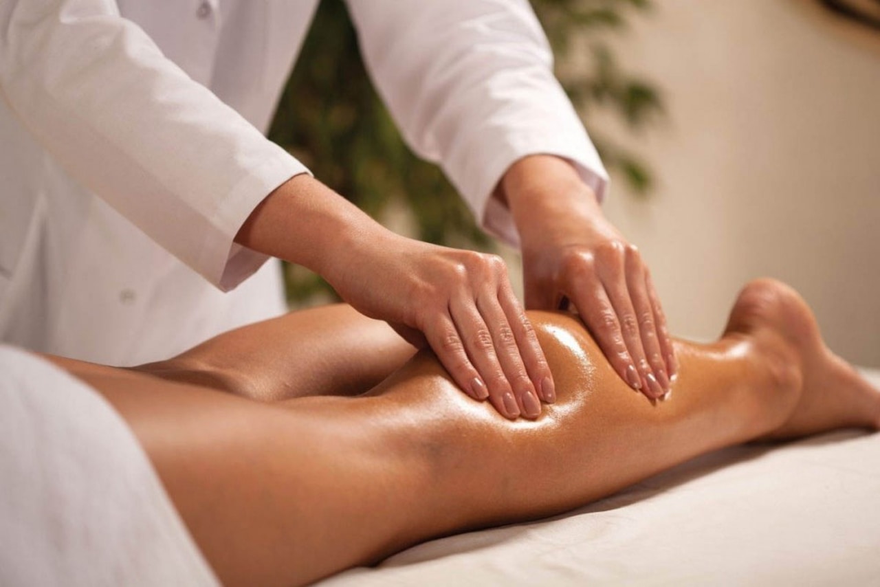 Масажист робить масаж ніг клієнту. Процес виглядає розслаблюючим та професійним, проводиться у спокійній обстановці, що вказує на спа чи масажний кабінет. Масажист використовує обидві руки для масажу литок, що, ймовірно, сприяє розслабленню м'язів та покращенню кровообігу.