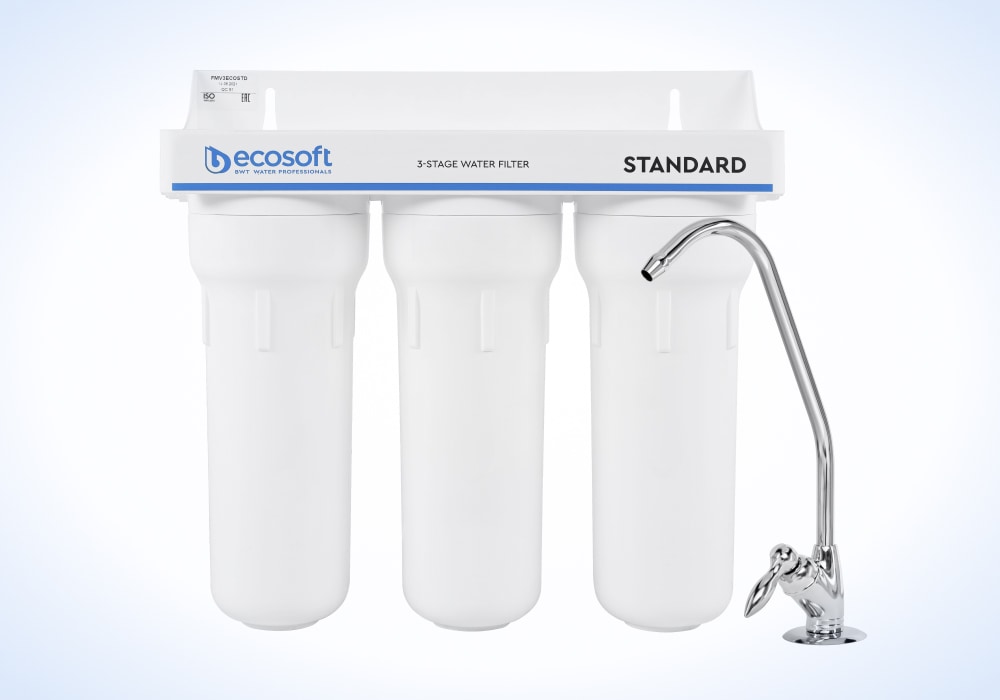 Трехэтапная система очистки воды бренда "ecosoft" включает три белые фильтр-корпуса под названием "STANDARD" и стильный кран хромированного вида справа.