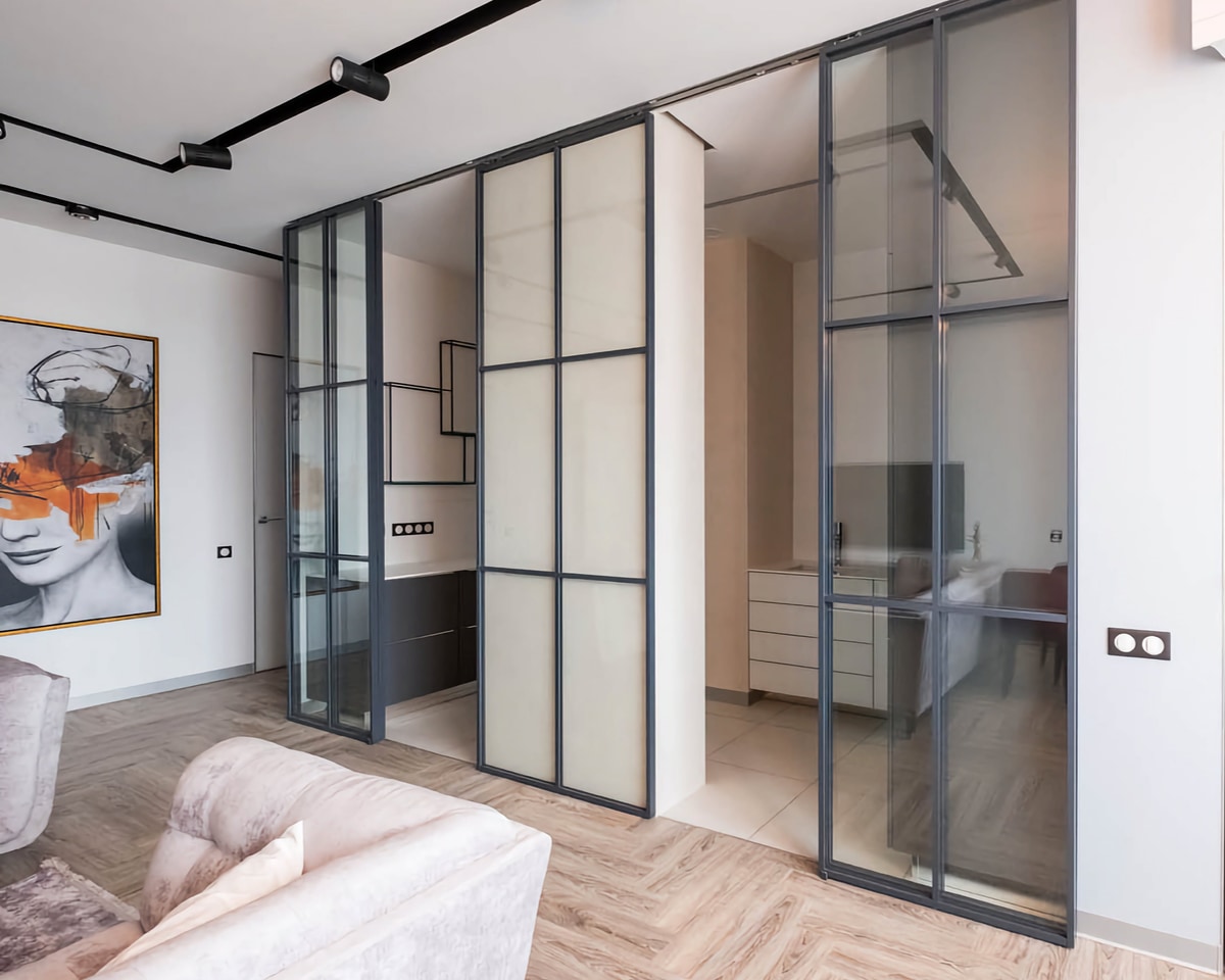 Современная гостиная с прозрачными стеклянными перегородками, мягким светлым диваном и крупным искусственным изображением на стене.