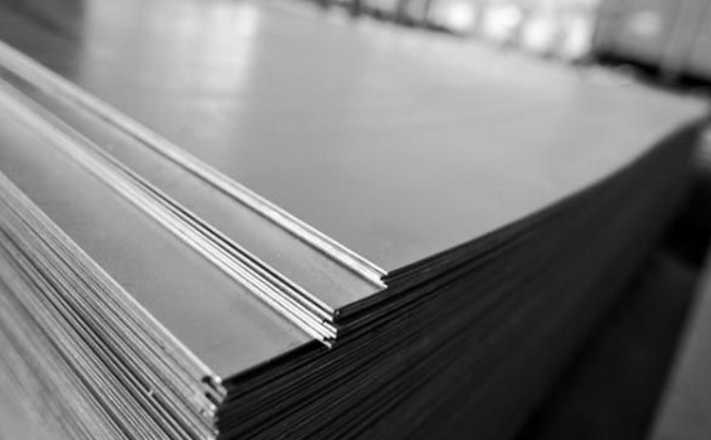 Чорно-біла фотографія стопки сталевих листів на виробничому обладнанні.