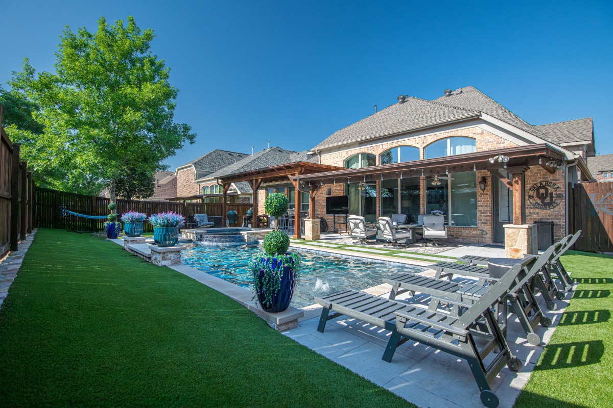 Современный двор частного дома с бассейном, шезлонгами для отдыха и террасой под навесом