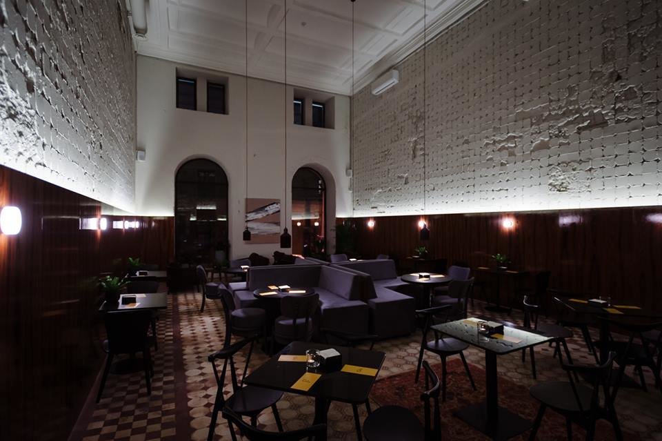 Фото интерьера ресторана с высокими 7-ми метровыми потолками, кафельной плиткой, мягкими диванами и небольшими квадратными столиками