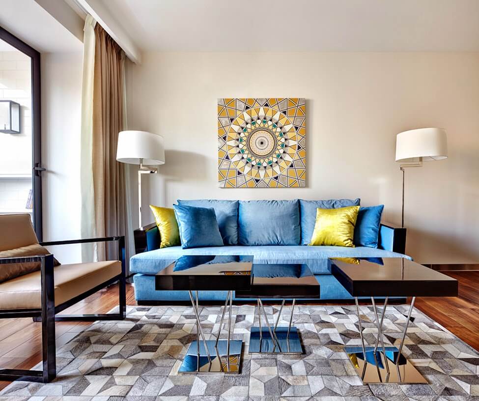 Геометрическое солнце на картине, оттеняемое желтыми диванными подушками,добавляет яркости пастельному оформлению