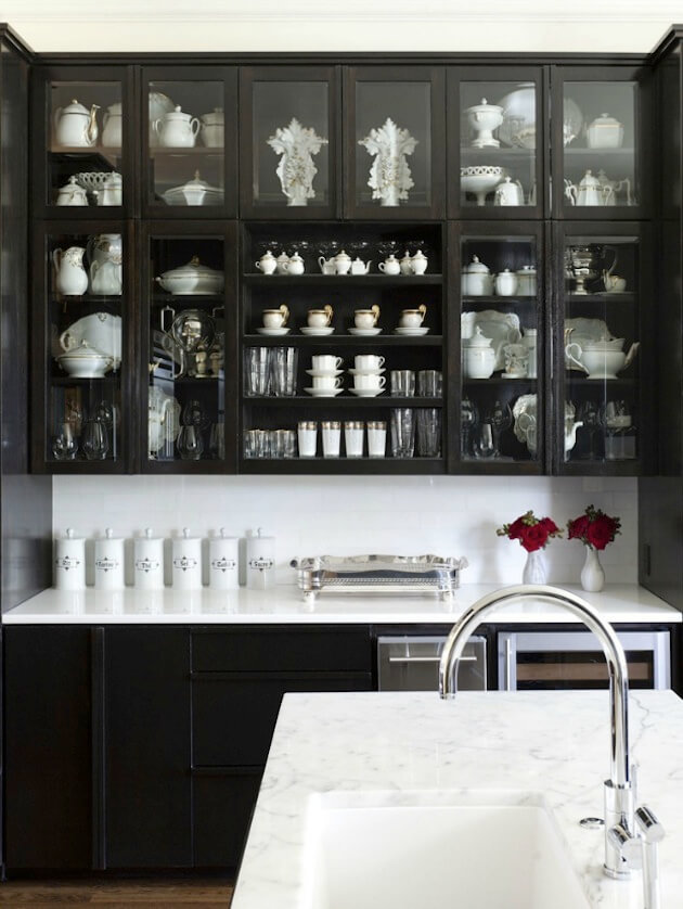 Беспроигрышное сочетание черного и белого отлично применяется на темной кухне в виде акцентного белого фартука и светлой посуды в стеклянных шкафчиках.